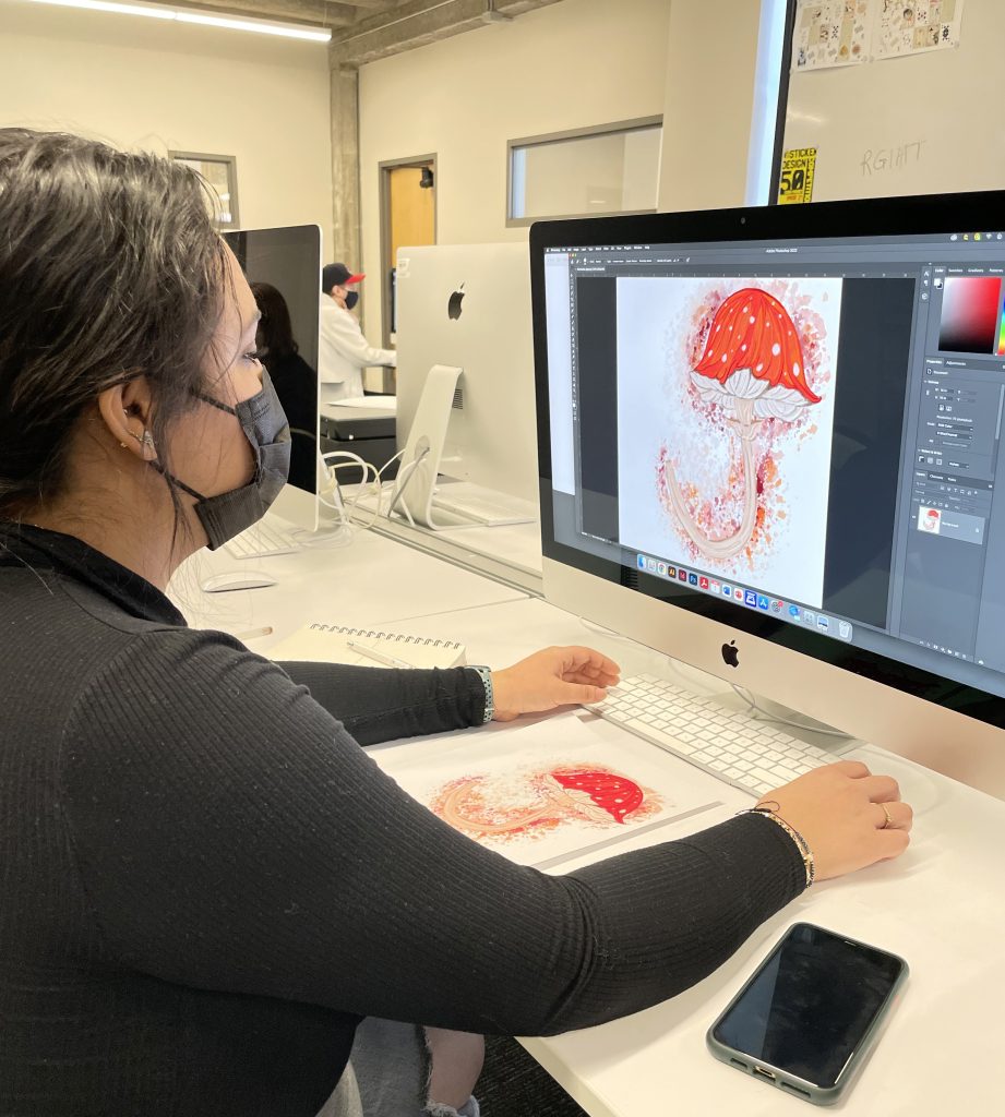 A student working on a graphic of a font shaped as a mushroom on a computer.
