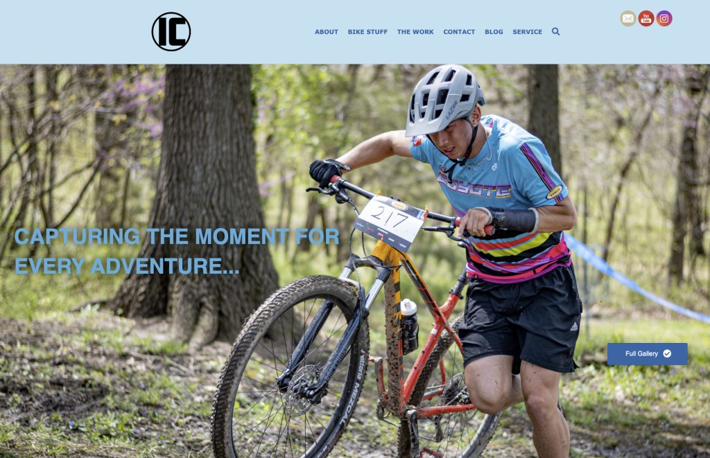 The design of the home page of a website with a photo of a biker walking his decorative bike through mud.